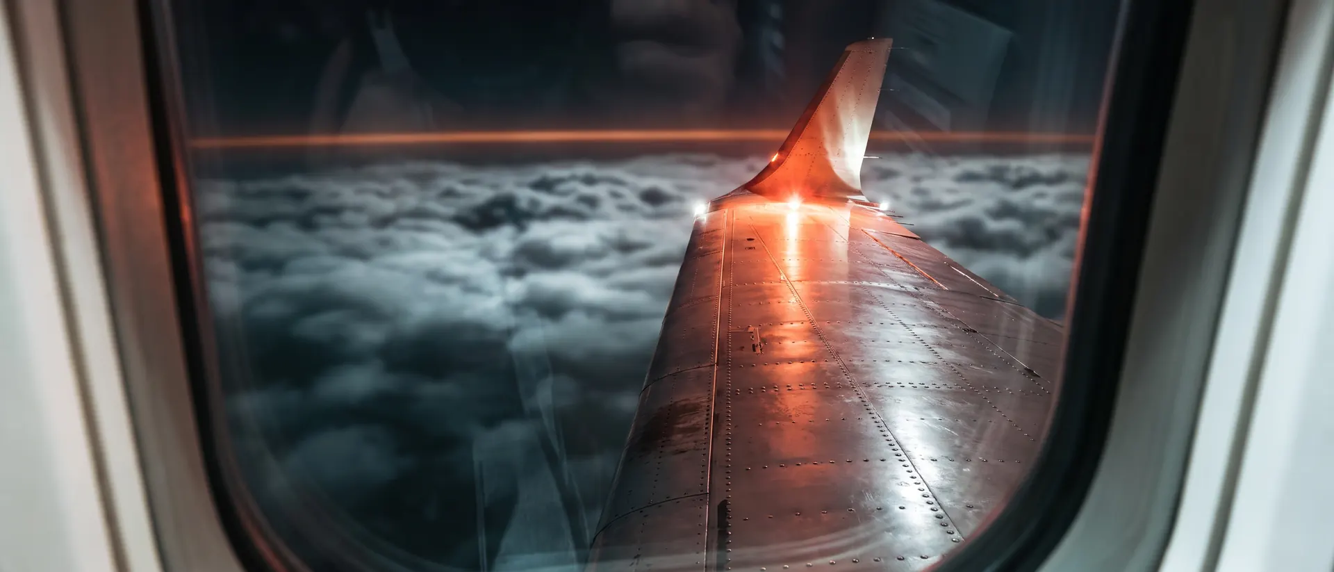 Winglet y luz estroboscópica de una aeronave sobre un manto de nubes de noche